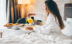 Woman eating breakfast in the hotel room. Room service breakfast in hotel room.
